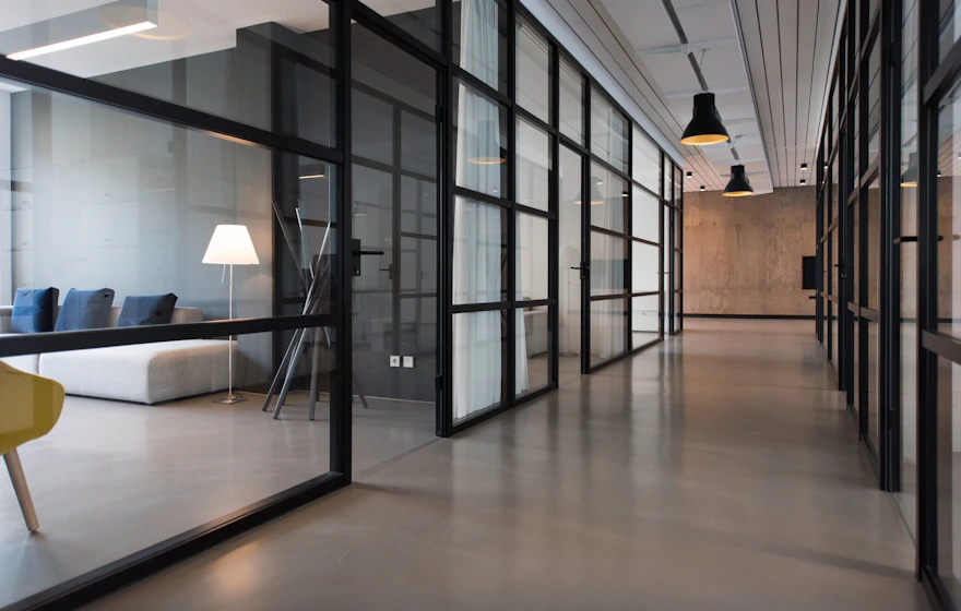 Glass-walled meeting rooms along a modern corporate office corridor